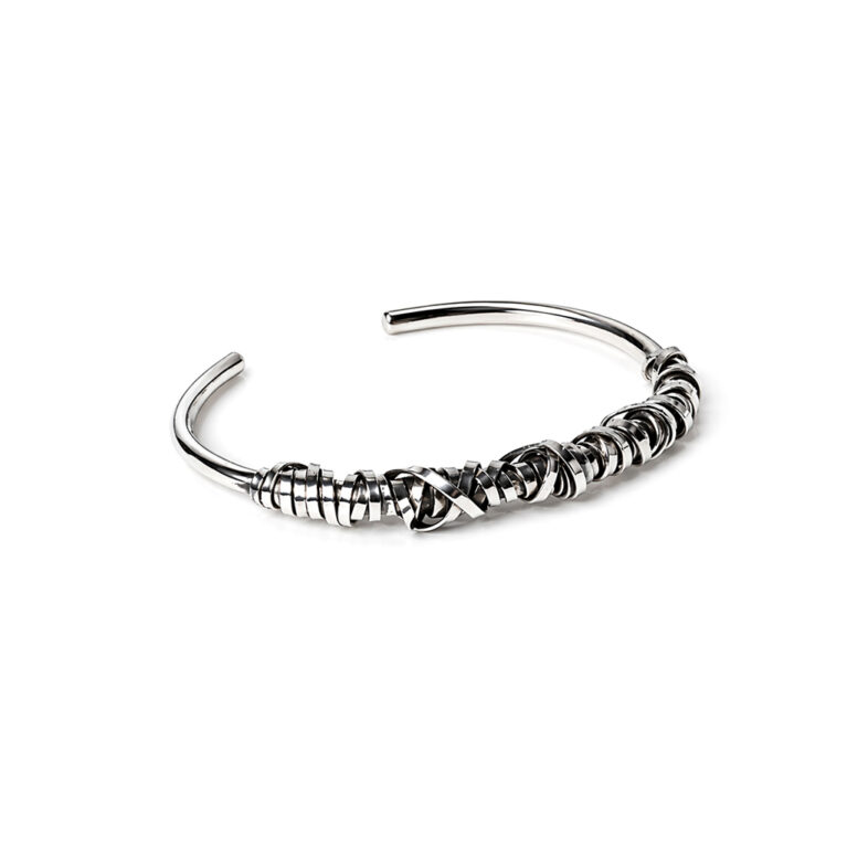 Handcrafted sterling silver wire cuff bracelet with layered sculptural design on a white background.