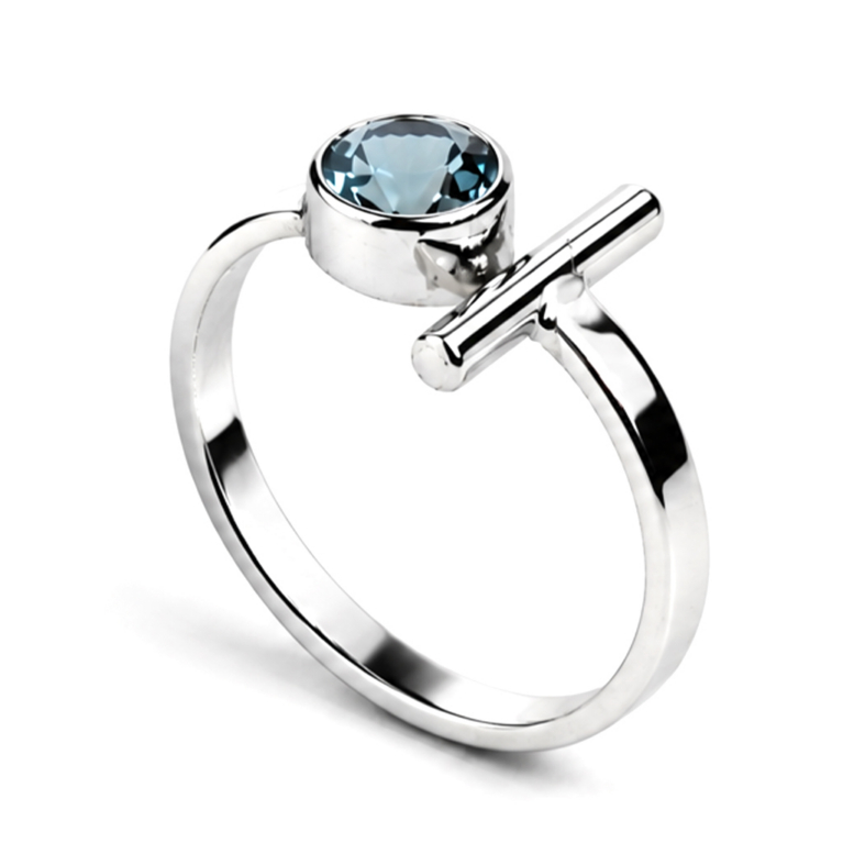 Handmade sterling silver ring featuring a genuine round blue topaz in a polished bezel setting with a modern geometric bar accent and an ultra mirror polished 925 sterling silver band on a white background.